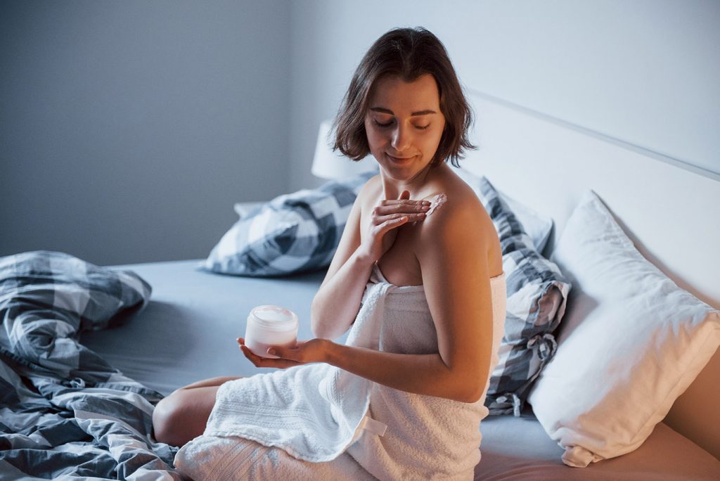 What's the difference between home and clinical peels? - woman sits on the bed and use cosmetics to clean h CBV2T4E Botox Nottingham Dermal Fillers Beeston West_Bridgford Skin Tag Removal Wart Cheek Fillers Chesterfield Lincoln Leicester Beauty Skin Dermatology Treatments